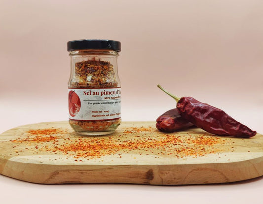 Sel au piment d'Espelette AOP Origine France 100g, présentation dans un pot sur planche en bois avec piments d'Espelette entiers