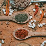 A flat lay of various organic spices and herbs on a wooden board, emphasizing natural culinary variety.
